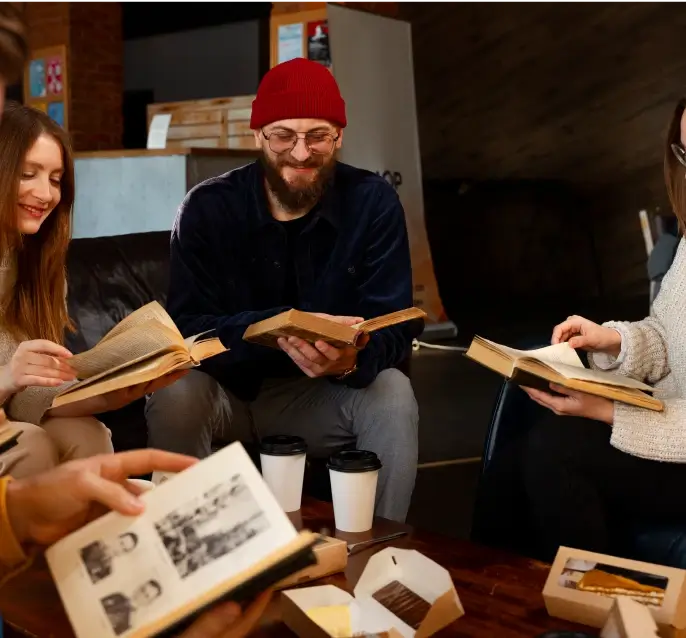 A group of people sitting together in a cozy setting, reading books and discussing ideas